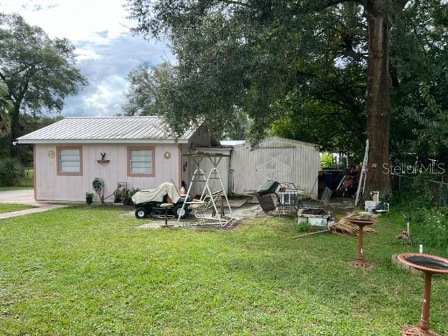 rear view of property featuring an outdoor structure and a yard