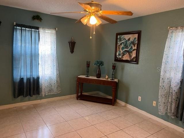 spare room with light tile flooring, a textured ceiling, a healthy amount of sunlight, and ceiling fan