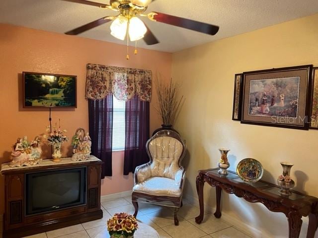 sitting room featuring light tile floors, ceiling fan, and a textured ceiling