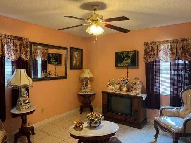 living area with light tile floors, ceiling fan, and a textured ceiling