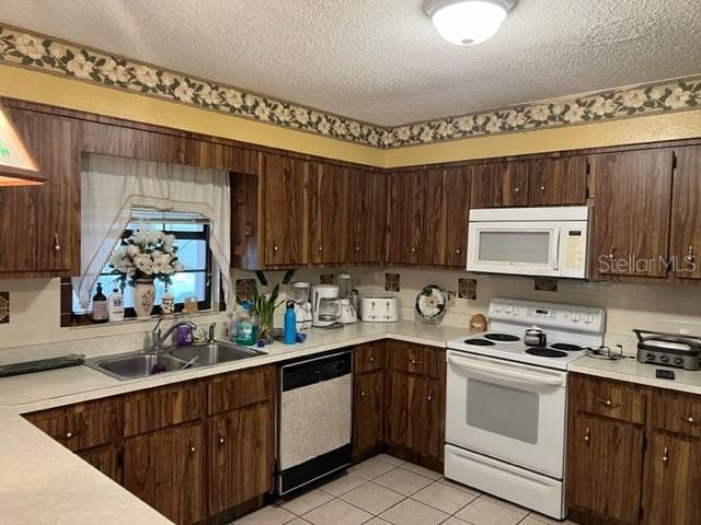 kitchen with light tile flooring, white appliances, a textured ceiling, and sink