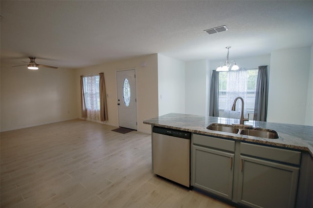 kitchen with ceiling fan with notable chandelier, sink, light hardwood / wood-style flooring, light stone counters, and stainless steel dishwasher