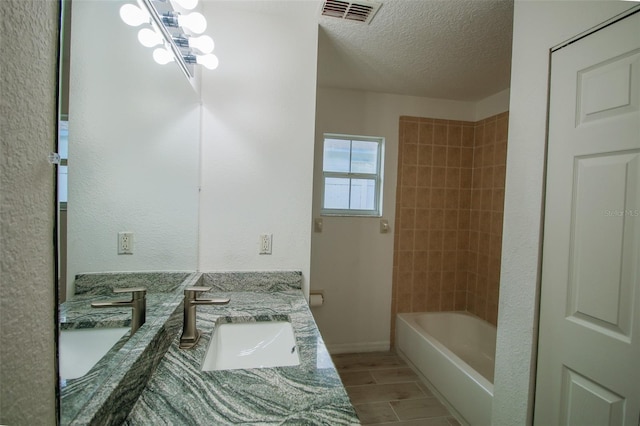 bathroom featuring tiled shower / bath combo, vanity, a textured ceiling, tile flooring, and a chandelier