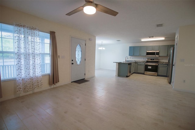 kitchen featuring appliances with stainless steel finishes, light hardwood / wood-style floors, ceiling fan, and sink