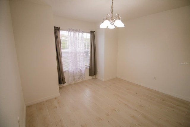 unfurnished room featuring light hardwood / wood-style floors and a notable chandelier