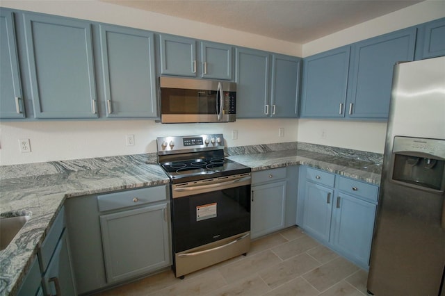 kitchen with light tile flooring, light stone countertops, and appliances with stainless steel finishes