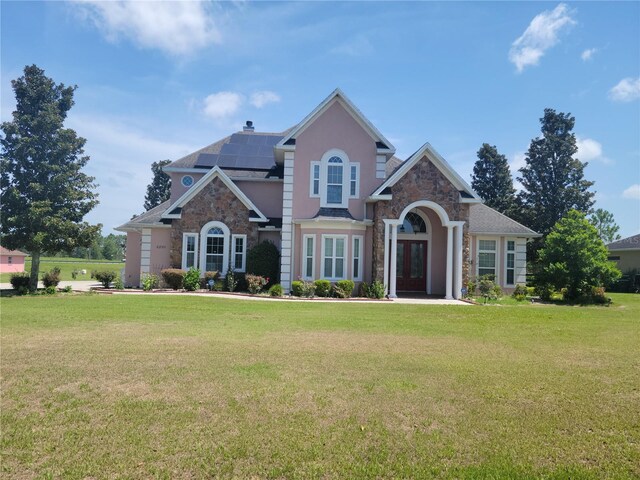 view of front facade with solar panels and a front yard