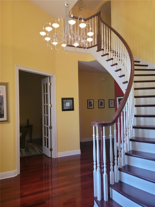 stairs featuring dark hardwood / wood-style floors, a notable chandelier, and a high ceiling