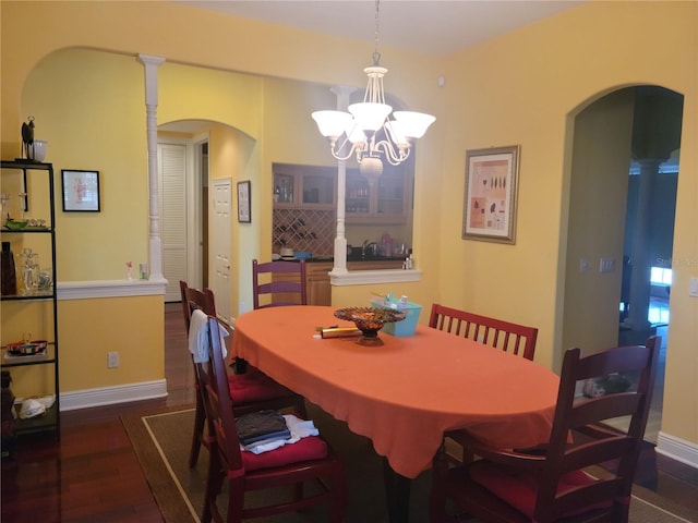 dining room featuring an inviting chandelier, dark hardwood / wood-style flooring, and decorative columns