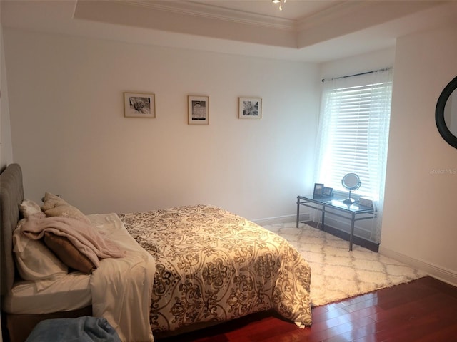 bedroom featuring crown molding, a raised ceiling, and hardwood / wood-style flooring