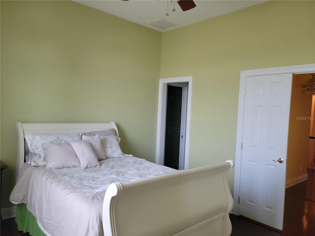 bedroom with a closet, dark wood-type flooring, a spacious closet, and ceiling fan