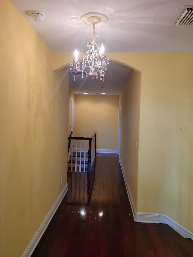 corridor featuring an inviting chandelier and dark hardwood / wood-style floors