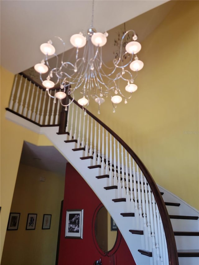 stairway featuring an inviting chandelier and a high ceiling