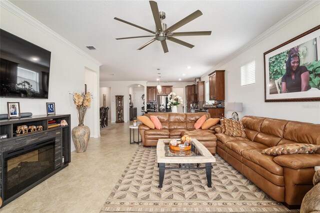 living room with light tile floors, ceiling fan, and ornamental molding