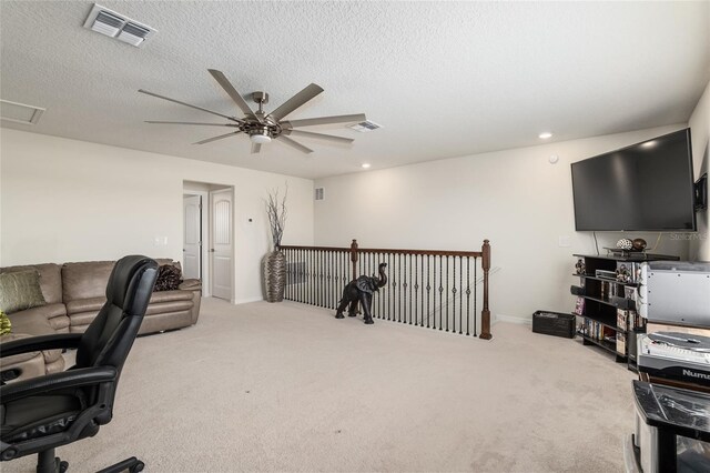 office area featuring light carpet, a textured ceiling, and ceiling fan