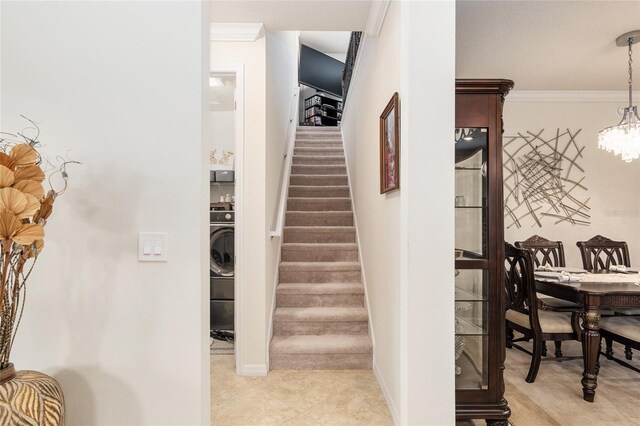 interior space with crown molding, washer / clothes dryer, a notable chandelier, and light tile floors