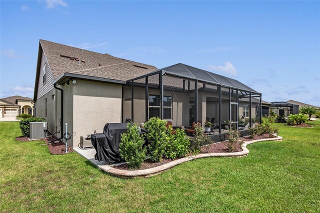 rear view of house with a lawn, a lanai, and central air condition unit