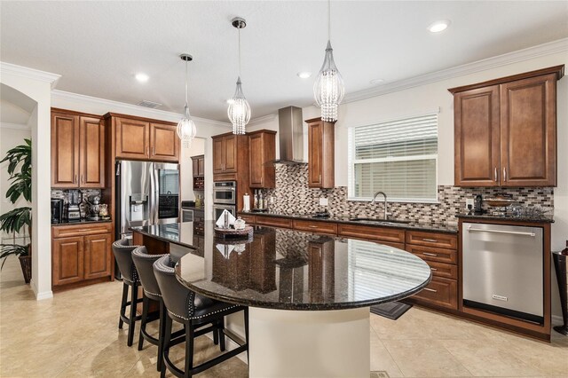 kitchen featuring sink, stainless steel appliances, a center island, wall chimney exhaust hood, and pendant lighting