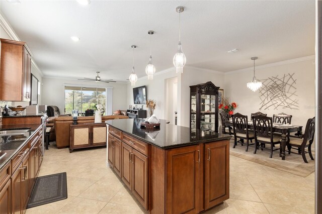 kitchen with light tile floors, dark stone countertops, decorative light fixtures, ceiling fan with notable chandelier, and a center island