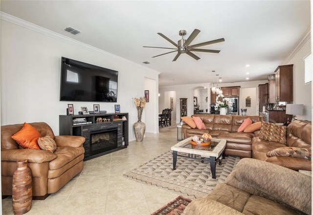 living room featuring light tile flooring, ceiling fan with notable chandelier, and crown molding