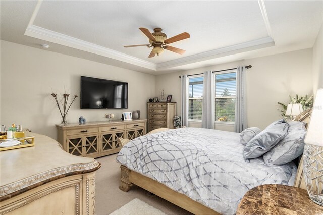 bedroom with light carpet, a raised ceiling, ornamental molding, and ceiling fan