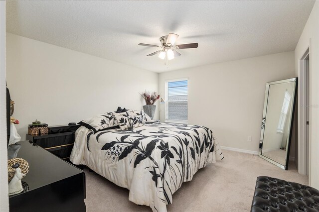 bedroom featuring a textured ceiling, ceiling fan, and light colored carpet