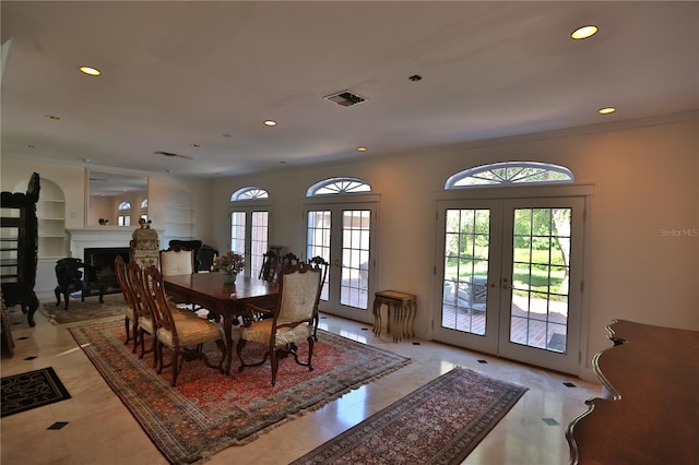 dining space featuring built in features, light tile floors, french doors, and crown molding