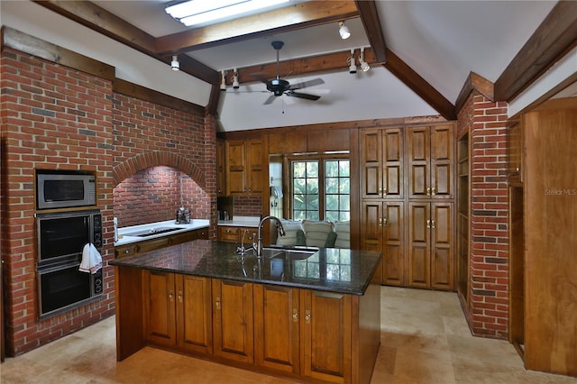 kitchen with brick wall, ceiling fan, black appliances, dark stone countertops, and sink