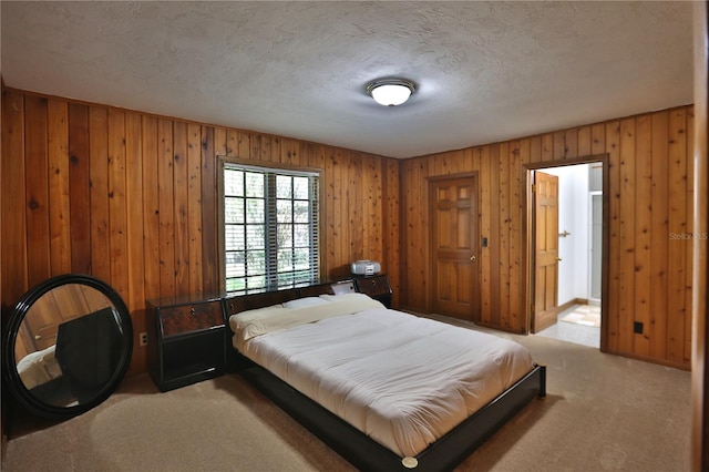 bedroom with wooden walls, light carpet, and a textured ceiling