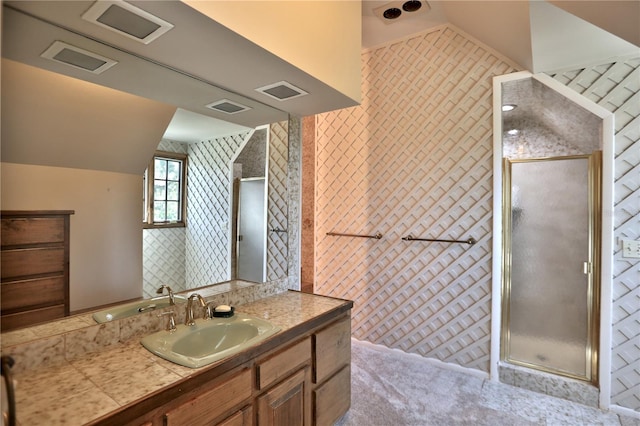 bathroom with vanity, a shower with door, and vaulted ceiling