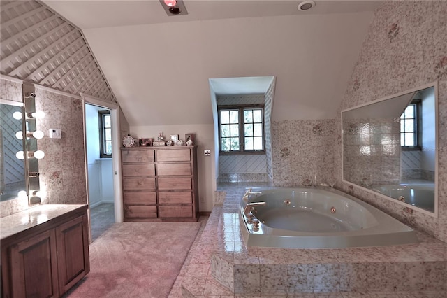 bathroom featuring vaulted ceiling, vanity, and a relaxing tiled bath