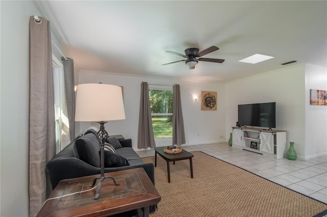 tiled living room featuring a skylight, ceiling fan, and ornamental molding