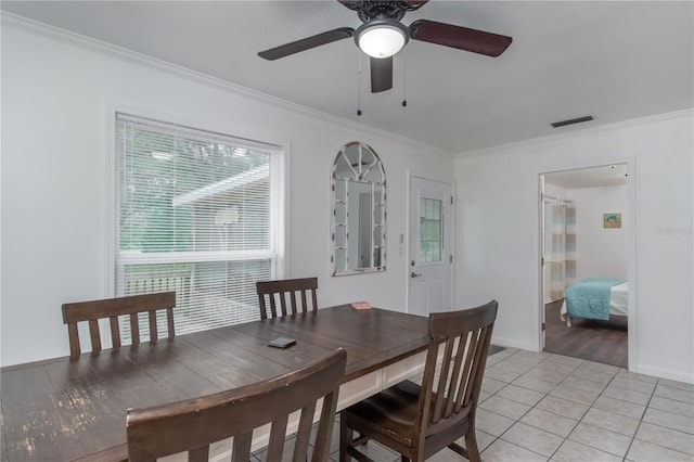 dining space with crown molding, ceiling fan, a healthy amount of sunlight, and light tile flooring