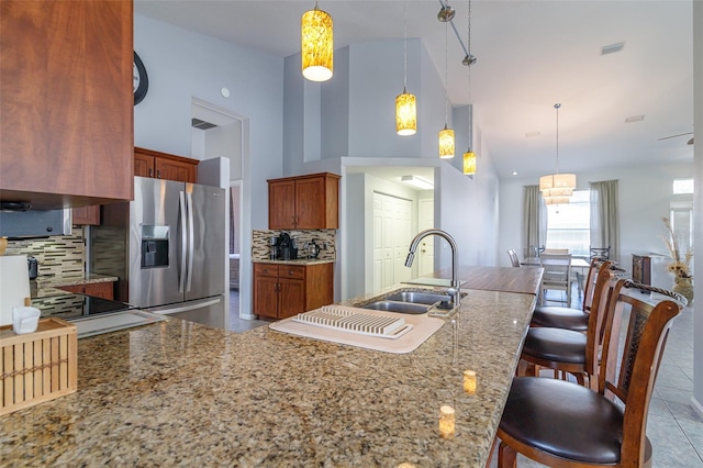 kitchen featuring stainless steel fridge, backsplash, pendant lighting, and a kitchen bar