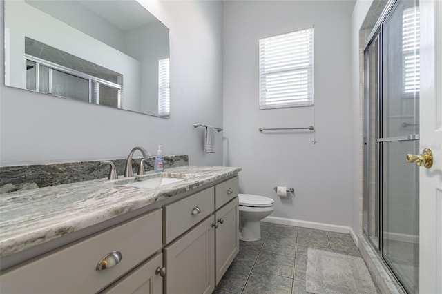 bathroom featuring toilet, tile floors, a shower with shower door, and vanity with extensive cabinet space