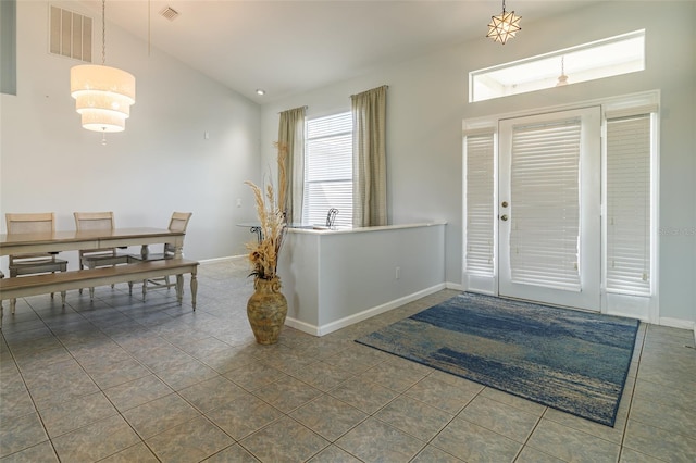 foyer with dark tile flooring and high vaulted ceiling