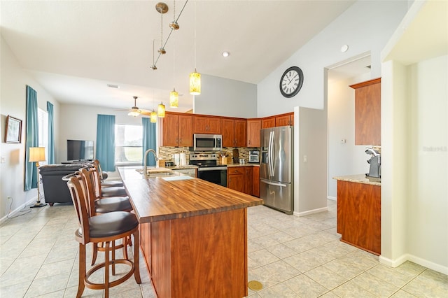 kitchen with stainless steel appliances, a kitchen bar, ceiling fan, backsplash, and hanging light fixtures