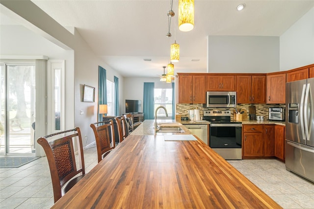 kitchen with backsplash, light tile floors, appliances with stainless steel finishes, and sink