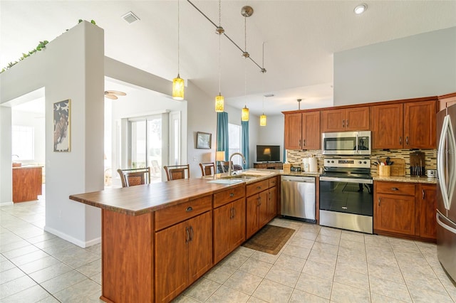 kitchen with backsplash, decorative light fixtures, light tile flooring, and appliances with stainless steel finishes