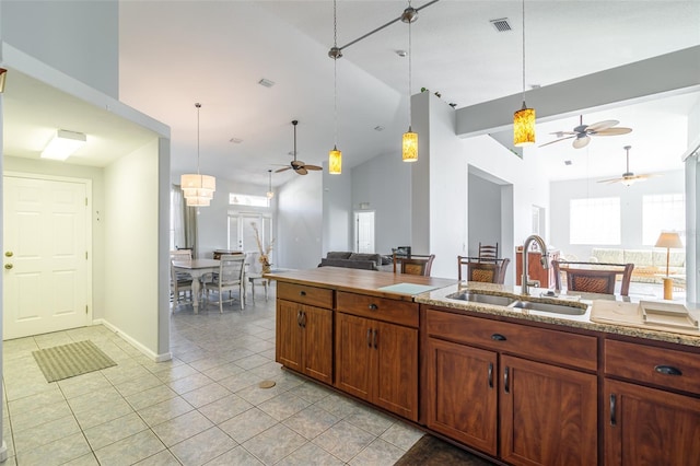 kitchen featuring decorative light fixtures, ceiling fan, light tile flooring, high vaulted ceiling, and sink