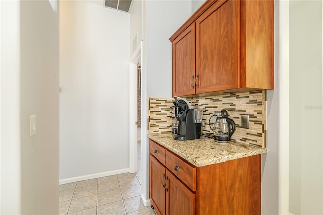 kitchen featuring backsplash, light tile floors, and light stone countertops