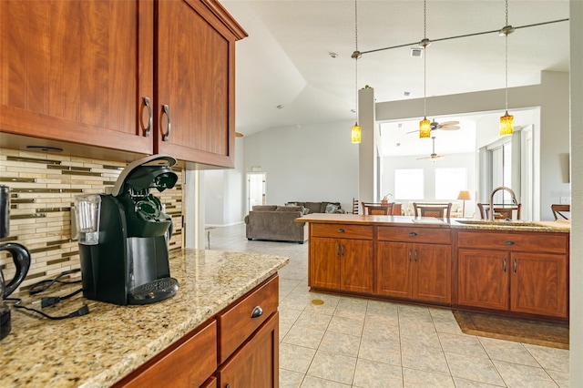 kitchen featuring backsplash, ceiling fan, light tile flooring, sink, and light stone counters