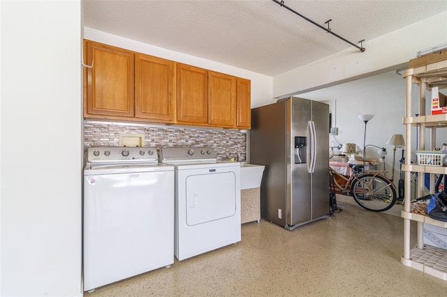 washroom featuring a textured ceiling, separate washer and dryer, and cabinets