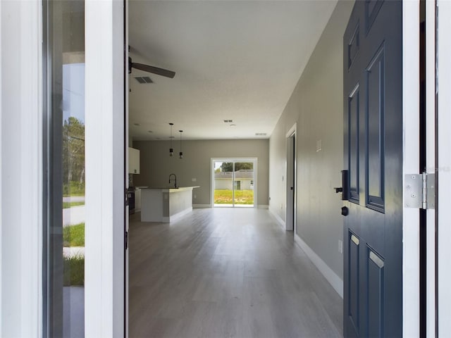 foyer entrance with light hardwood / wood-style flooring, ceiling fan, and sink