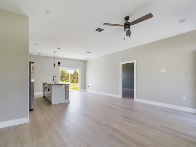 unfurnished living room featuring ceiling fan, sink, and light hardwood / wood-style flooring