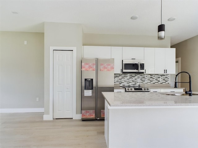 kitchen with pendant lighting, sink, light hardwood / wood-style flooring, stainless steel appliances, and white cabinetry