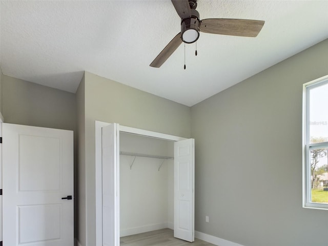 unfurnished bedroom with light hardwood / wood-style floors, a closet, ceiling fan, and multiple windows