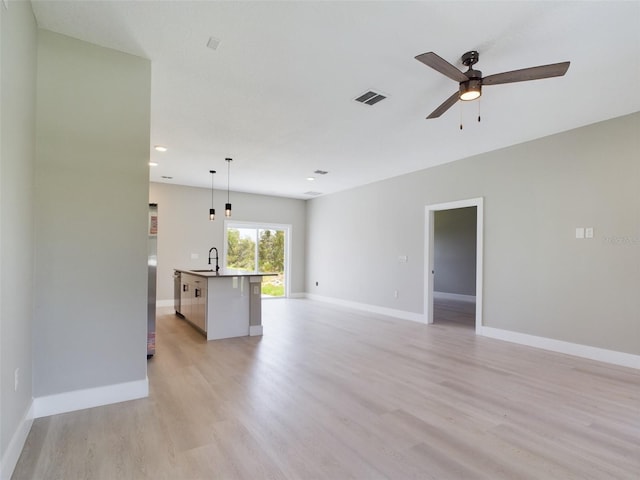 empty room featuring light hardwood / wood-style floors, ceiling fan, and sink