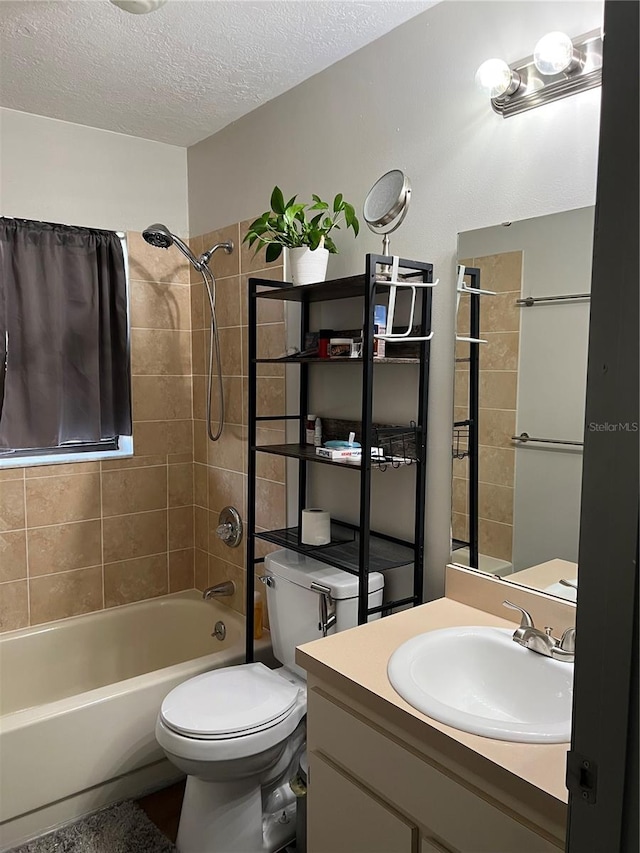 full bathroom featuring tiled shower / bath combo, toilet, a textured ceiling, and vanity