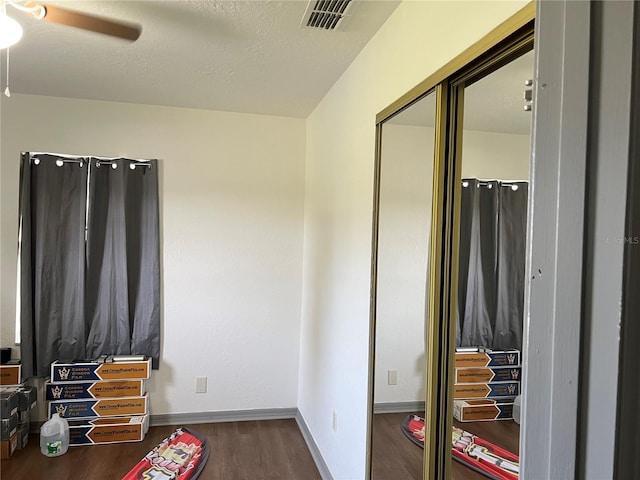 bedroom with ceiling fan, a textured ceiling, and dark hardwood / wood-style flooring